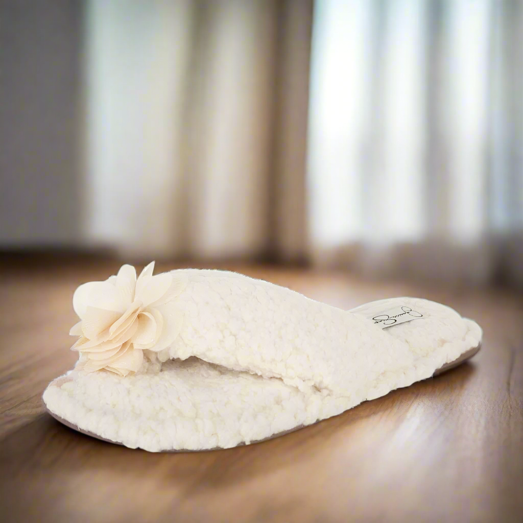 White fuzzy slippers with a flower on a white background