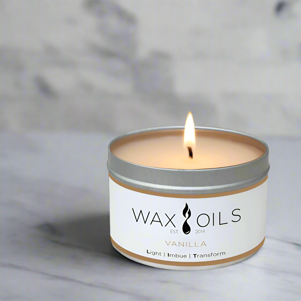 Candle in a tin labeled 'Wax Oils' with a vanilla scent on a white background